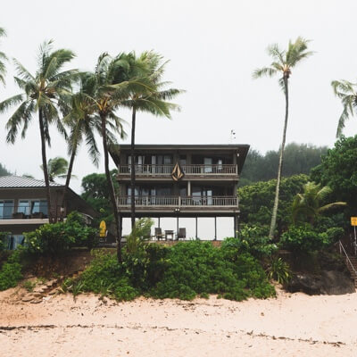 A beach house with a Volcom logo on the balcony, surrounded by palm trees.