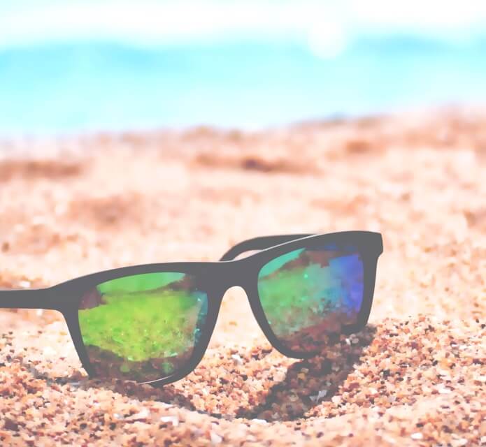 A pair of sunglasses on the beach on a sunny day.